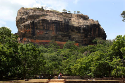 People on rock against sky