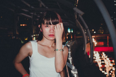 Portrait of young woman standing in footbridge at night