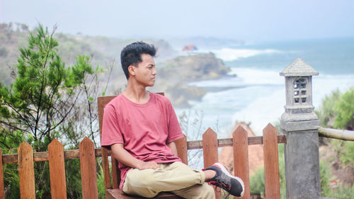 Thoughtful young man sitting against sea