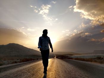 Rear view of man standing on road against sky