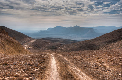 Dirt road on landscape against sky