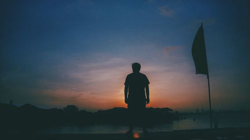 Silhouette man standing by sea against sky during sunset