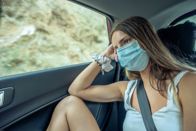 Close-up of girl wearing mask sitting in car