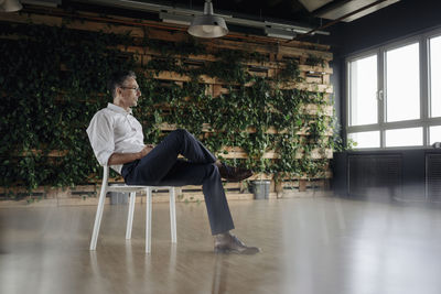 Businessman sitting on chair in green office thinking