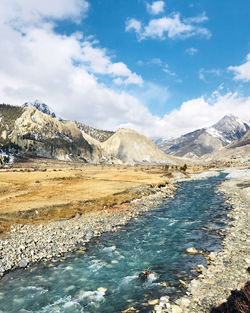 Scenic view of lake by snowcapped mountains against sky