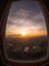 Cityscape seen through window during sunset