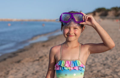 Portrait of young woman wearing sunglasses while standing at beach