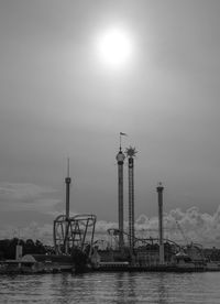 Cranes by river against sky