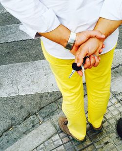 Rear view of man holding car keys standing on street