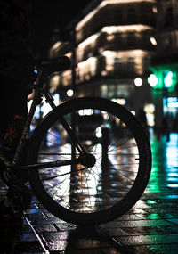 Reflection of illuminated bicycle on wet street at night