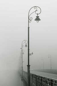 Street light by bridge against sky