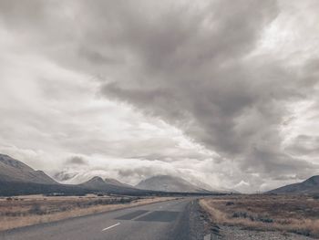 Country road along landscape against sky