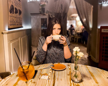 Emotions of lonely woman at cafe at the table drinking tea in the evening at cafe romantic light