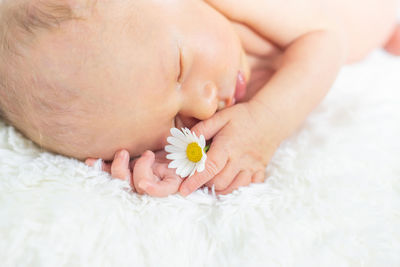 Cute baby with flower sleeping on bed at home