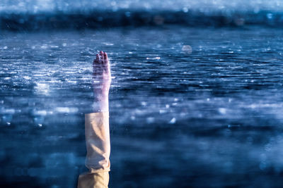 Cropped image of woman with hand raised swimming in sea