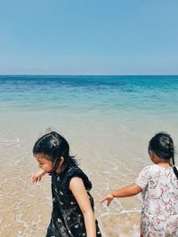 Friends enjoying at beach against sky