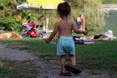 Rear view of shirtless boy playing in grass