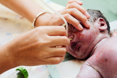 Cropped hands of doctor inserting medical pipe in newborn nose
