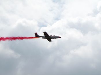 Low angle view of airplane flying against cloudy sky