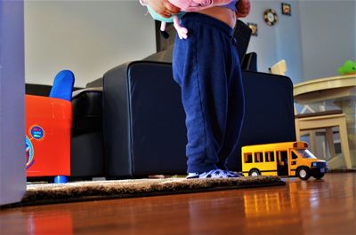 Low section of man with toy standing on table at home