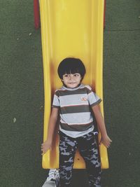 High angle view of cute boy playing on slide in playground