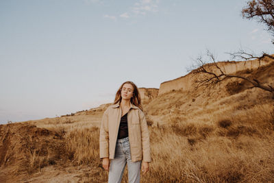 Portrait of woman standing by plants against sky