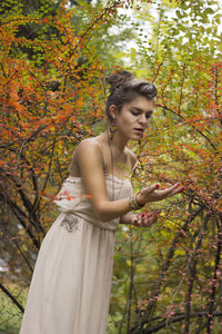 Young woman standing against tree during autumn