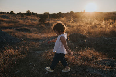 Side view of child standing on field during sunset