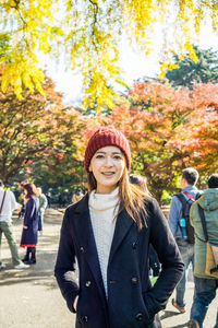 Portrait of smiling woman standing in park during autumn