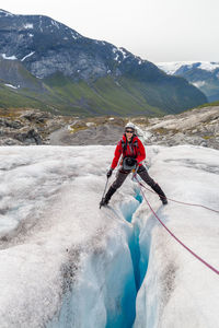 Happy female hiker standing on glacier crack against mountain