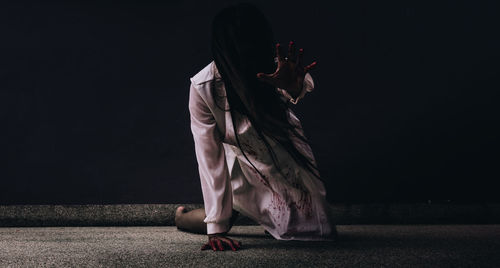 Young woman with halloween make-up lying on floor in darkroom