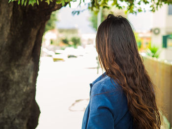 Rear view of girl standing against trees