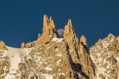 Idyllic shot of moon over rocky mountains against clear sky