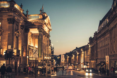 Road amidst illuminated against clear sky in city at night