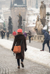 Rear view of people walking on street in city