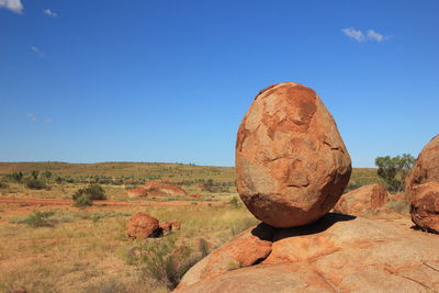 Rocks on landscape against clear blue sky