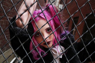 Portrait of woman seen through chainlink fence