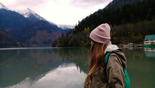 Side view of woman by lake against mountains