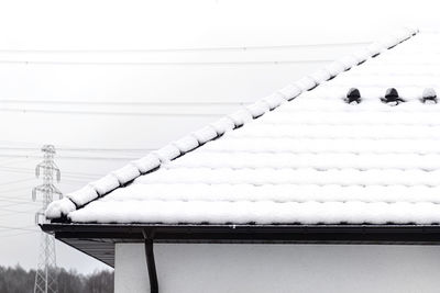 The roof of a single-family house is covered with snow against a cloudy sky