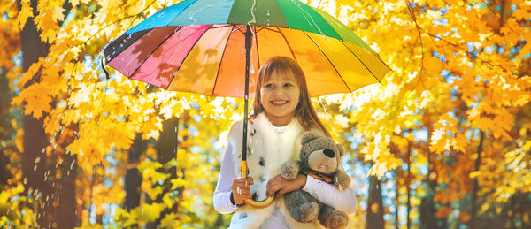 Cute girl holding umbrella at autumn forest