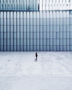 Man walking on footpath against building in city