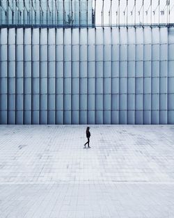 Man walking on footpath against building in city