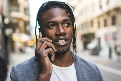 Close-up of young man talking on mobile phone in city