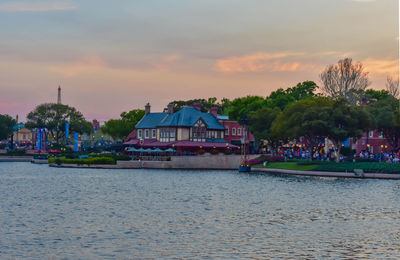 Scenic view of river by buildings against sky during sunset
