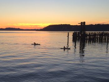 Silhouette boats in calm sea at sunset