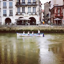 People in boat on canal against buildings in city