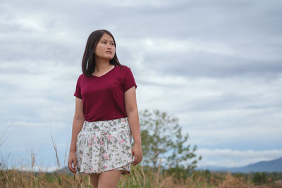 Beautiful young woman standing on land against sky