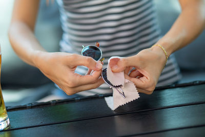 Midsection of woman cleaning sunglasses