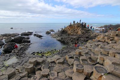 People on rock by sea against sky