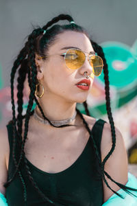 Close-up of young woman standing against graffiti wall